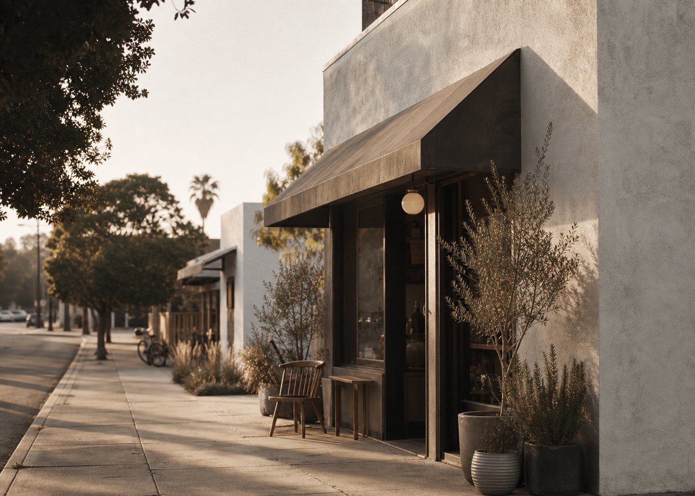 A quiet Los Angeles storefront on a tree-lined street at golden hour.